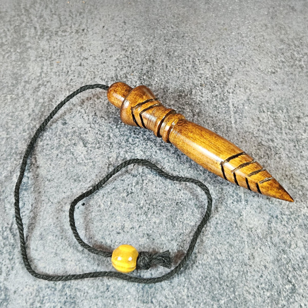 Pendule radiesthésie en chêne verni foncé, cordon noir visible posé au sol