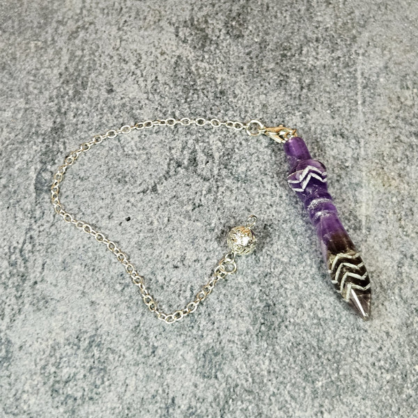 Pendule Thot en améthyste posé au sol, accessoire divinatoire pierre naturelle