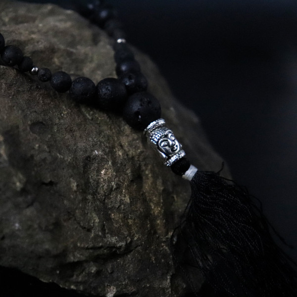 Détail collier pierre de lave Bouddha sur roche naturelle, bijou spirituel ancrage et protection