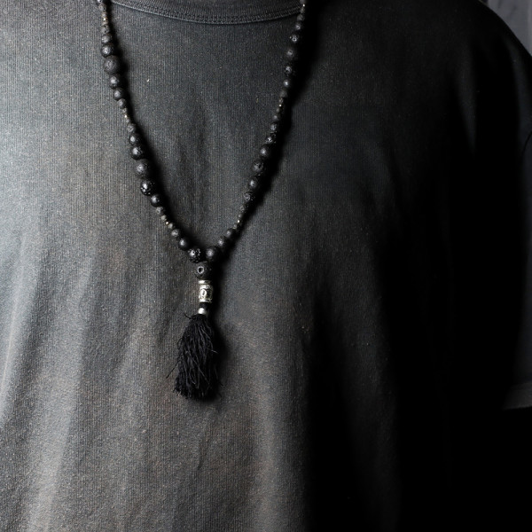 Collier pierre de lave porté avec pompon noir, bijou énergétique ancrage et sérénité
