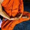 Détail des mains en méditation du moine en cire Luang Phor Sodh et de sa robe orange