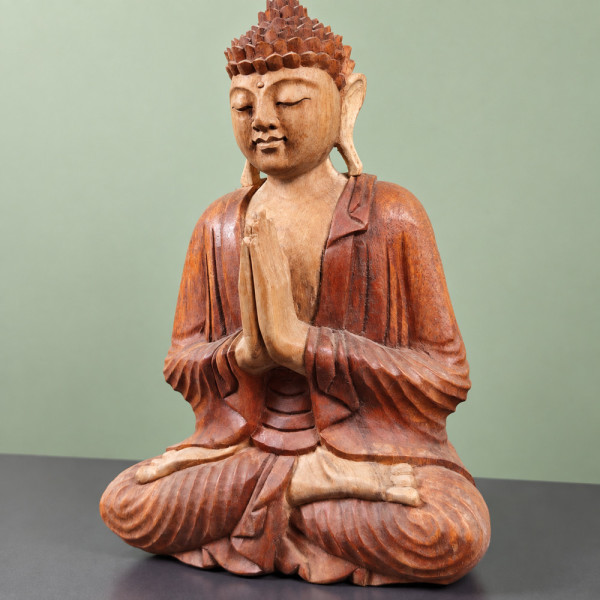 Bouddha de l’accueil en bois de suar, mains jointes et jambes croisées, visage tourné vers la gauche