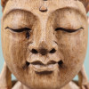 Très gros plan sur les yeux fermés, le nez et la bouche du Bouddha de l’accueil en bois de suar