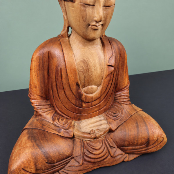 Gros plan des mains dans le giron, du veinage et des plis du vêtement du Bouddha en méditation en bois de suar
