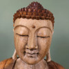Gros plan de face sur le visage aux yeux clos du Bouddha de la transmission en bois de suar sculpté à la main