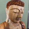 Détail de trois-quarts du visage et de la chevelure sculptée du Bouddha de la transmission en bois de suar