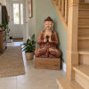 Bouddha de la transmission en bois de suar, 60 cm, au pied d’un escalier dans l’entrée de la Maison Namaste