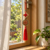 Porte-bonheur Feng Shui à pièces chinoises suspendu à une fenêtre dans une maison zen lumineuse