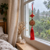Amulette Feng Shui de prospérité à pompon rouge suspendue à la fenêtre d’une chambre zen